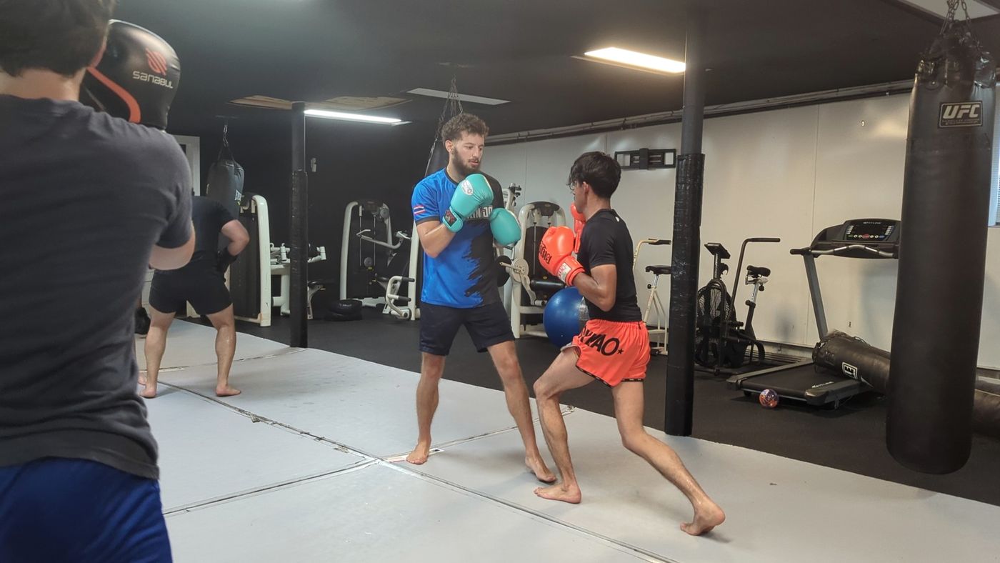Coach Elijah Halloun working with a student on the mat at Fight Mechanix