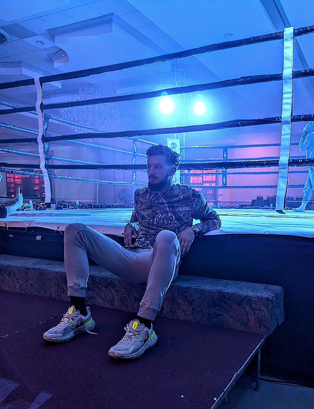 Coach Elijah Halloun sitting ringside under the event lights before a fight
