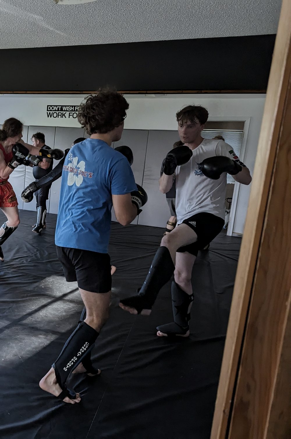 Fighters in gloves and shin guards working live rounds on the mat